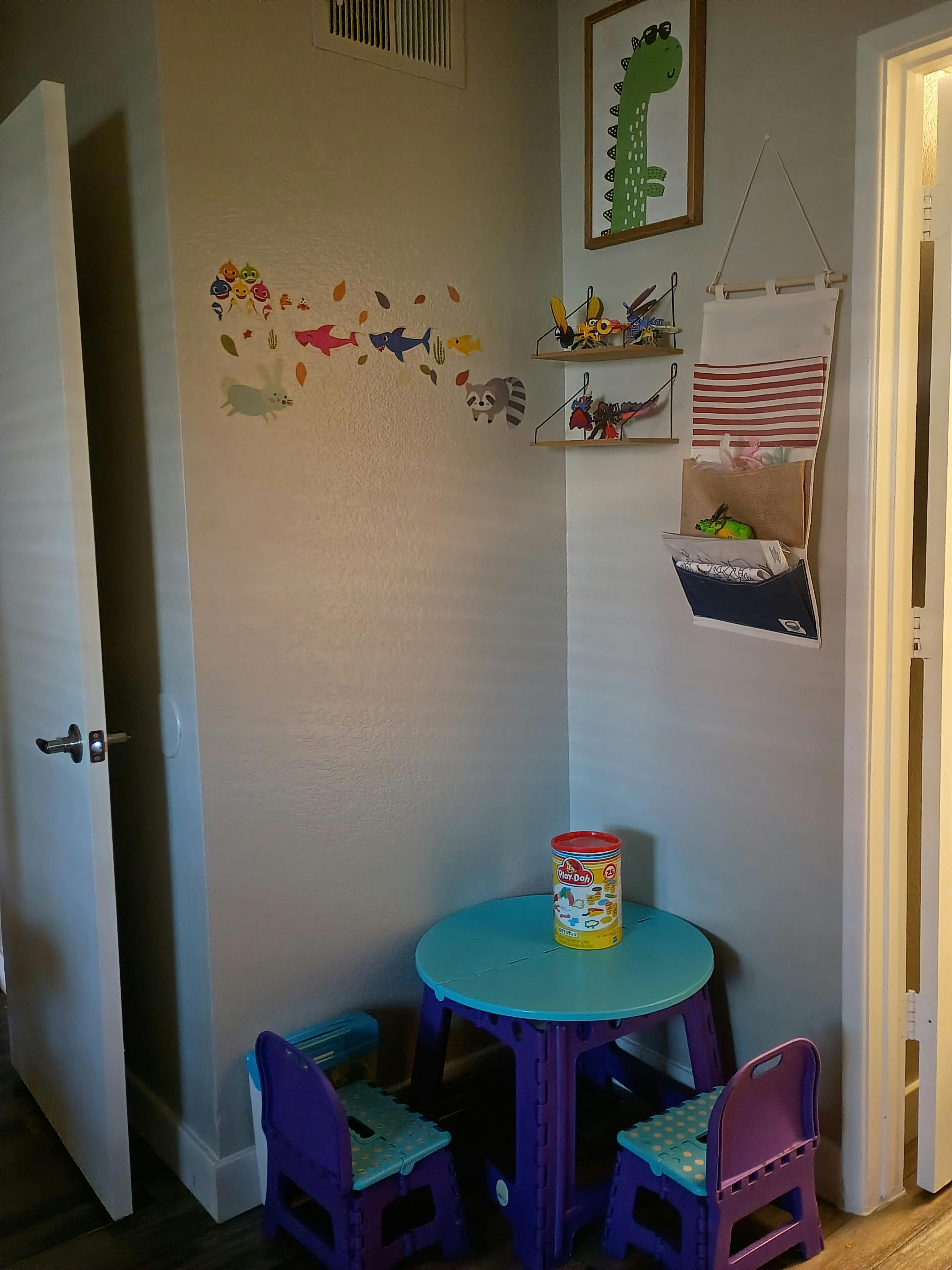 Small blue play table and chairs with children's toys and wall decorations