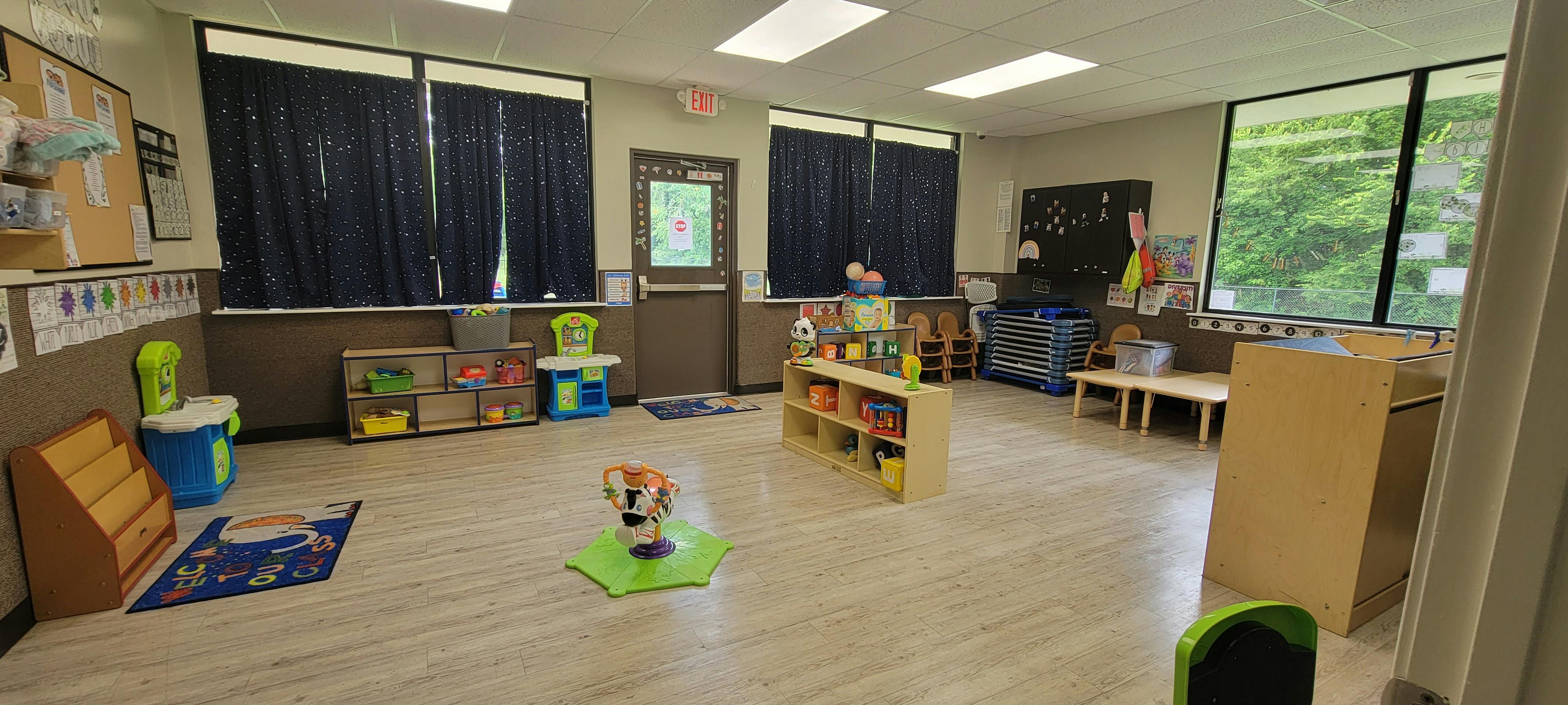 Empty classroom with toys, small tables, and cribs