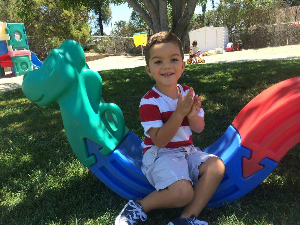 Child sitting on a colorful plastic seesaw