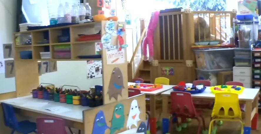 Classroom with tables, chairs, and shelves filled with supplies