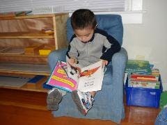 Child sitting in a chair reading a book