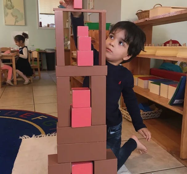 Child building a tower with blocks insets in a classroom