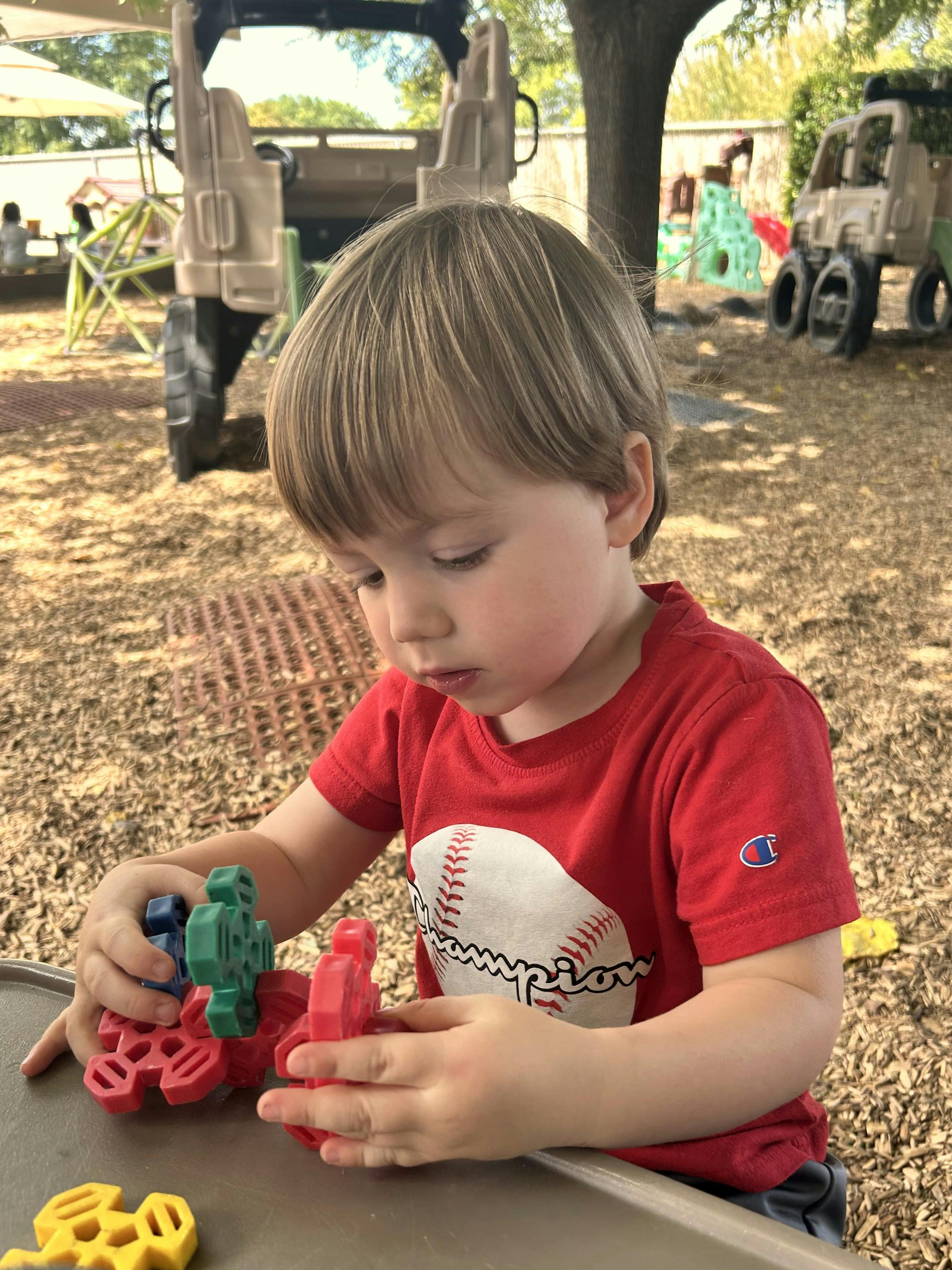 Child playing with plastic interlocking toy pieces at a playground