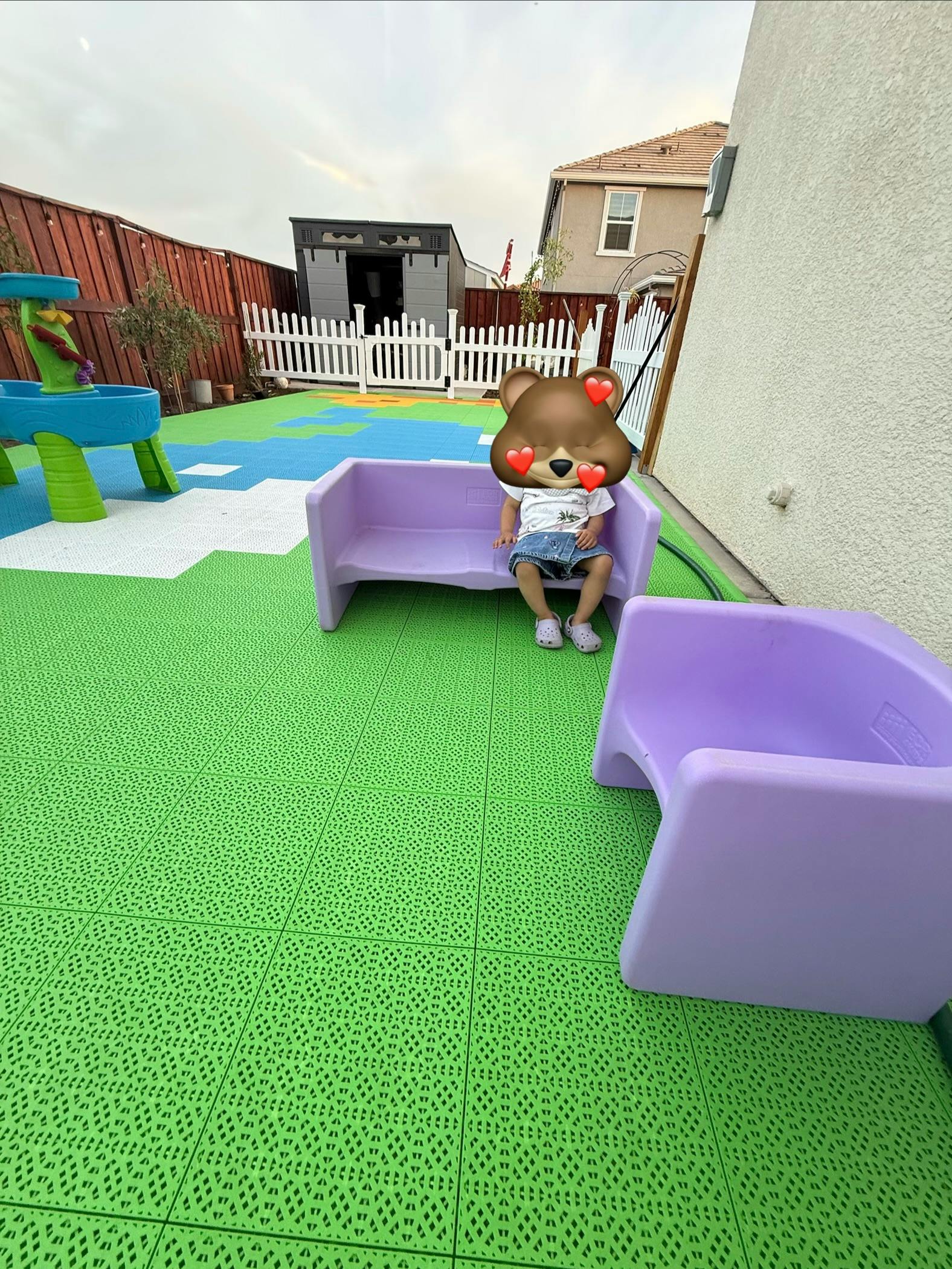 Child sitting on a small plastic bench in a backyard