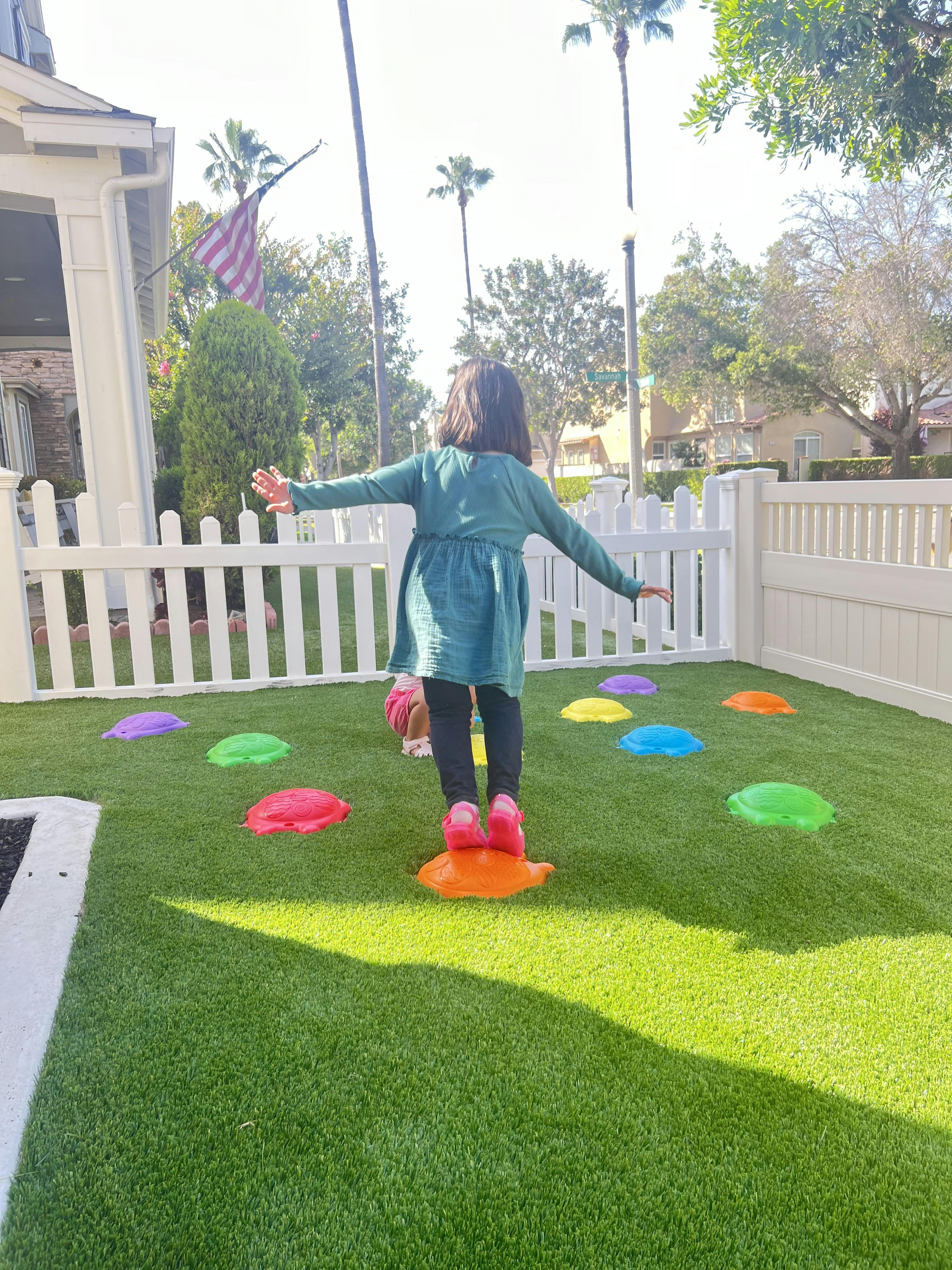Child balancing on a colorful stepping stone on artificial grass