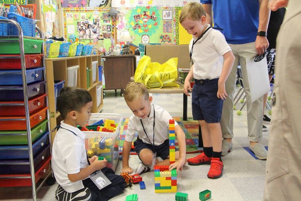 Two children playing with building blocks on the floor in a classroom