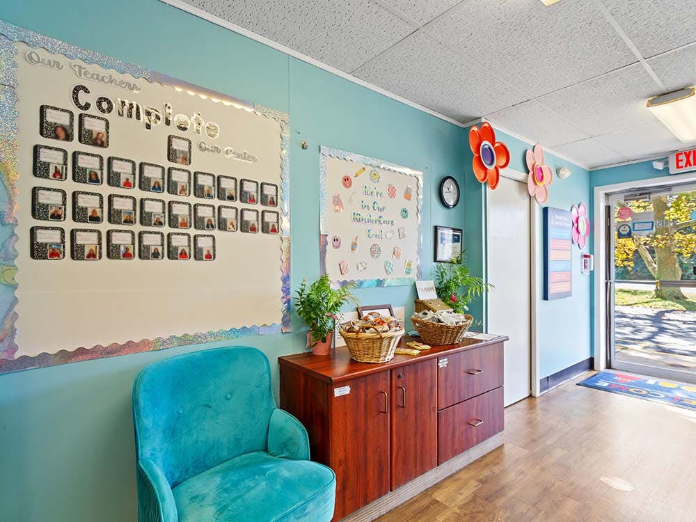 Bulletin boards in a colorful classroom entrance with a blue chair and white theme