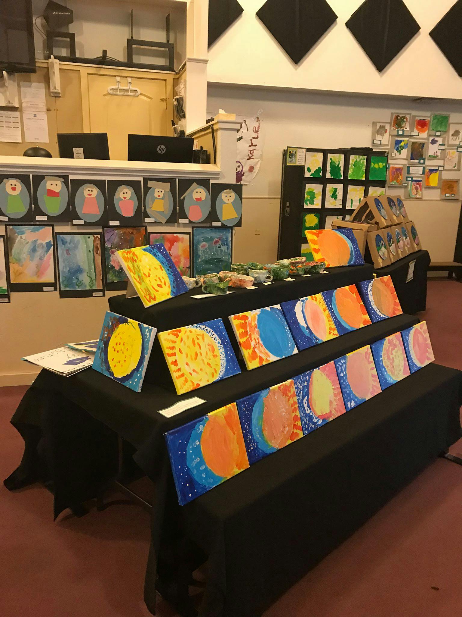 Children's artwork displayed on tables and walls in a room