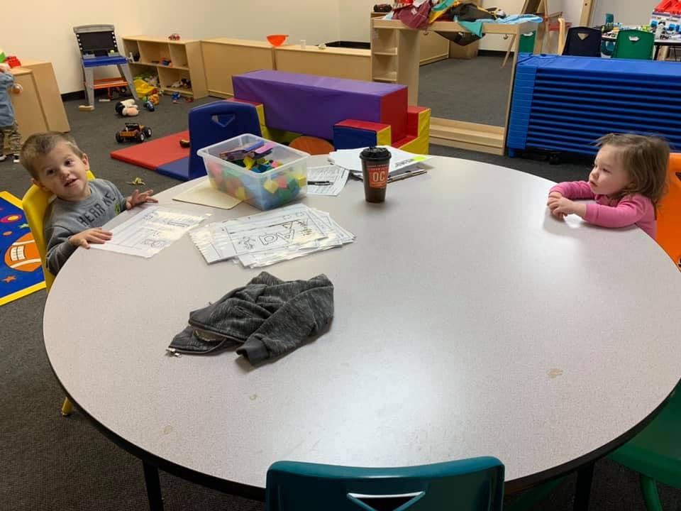 Two children sitting at a round table in a classroom