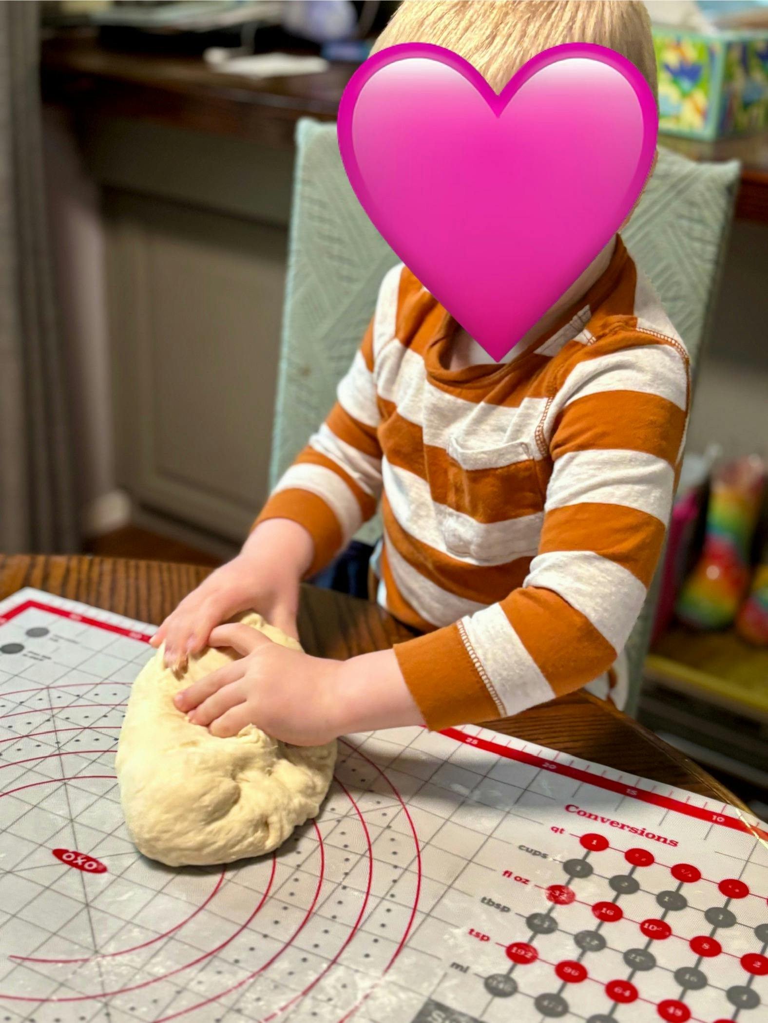 Child kneading dough on a baking mat