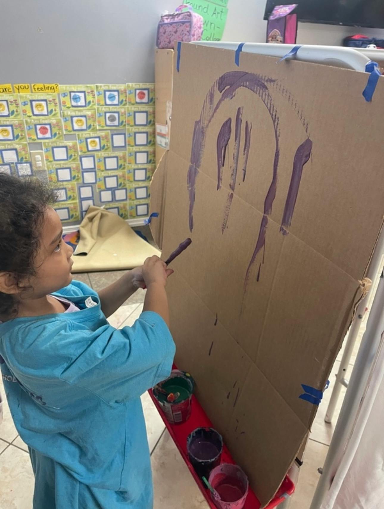 Child painting on cardboard in a classroom
