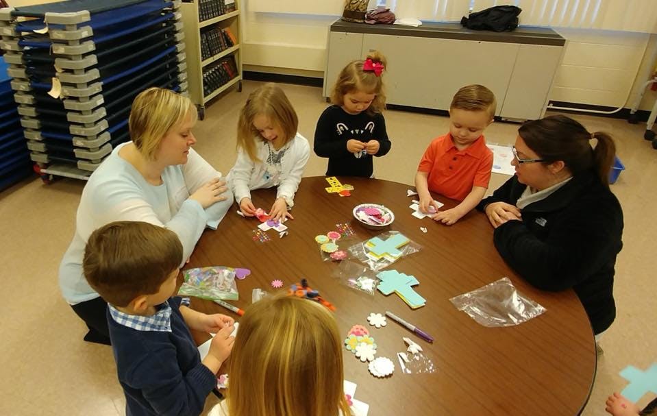 Adults and children sitting around a table doing crafts