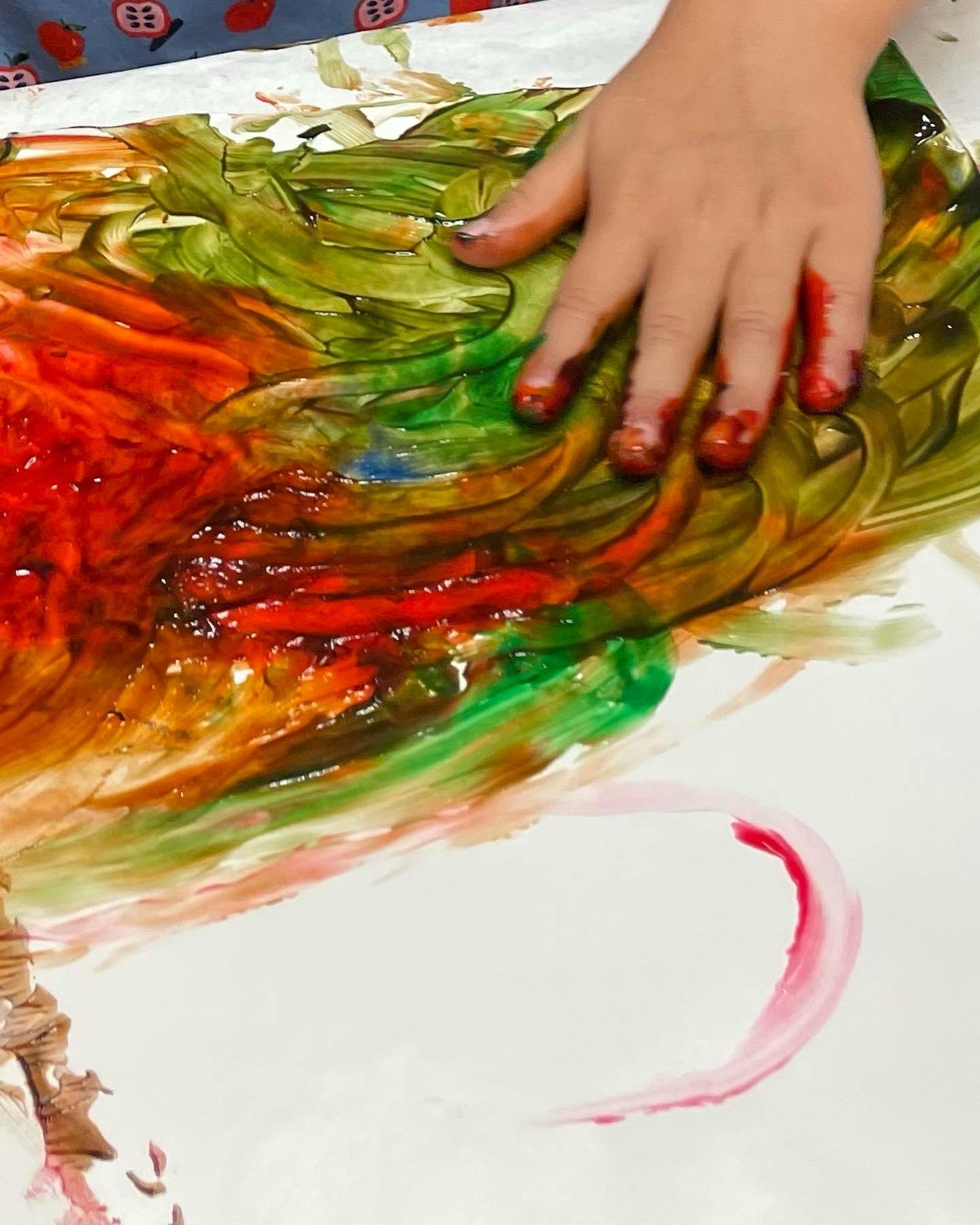 Child's hand finger painting with red and green paint