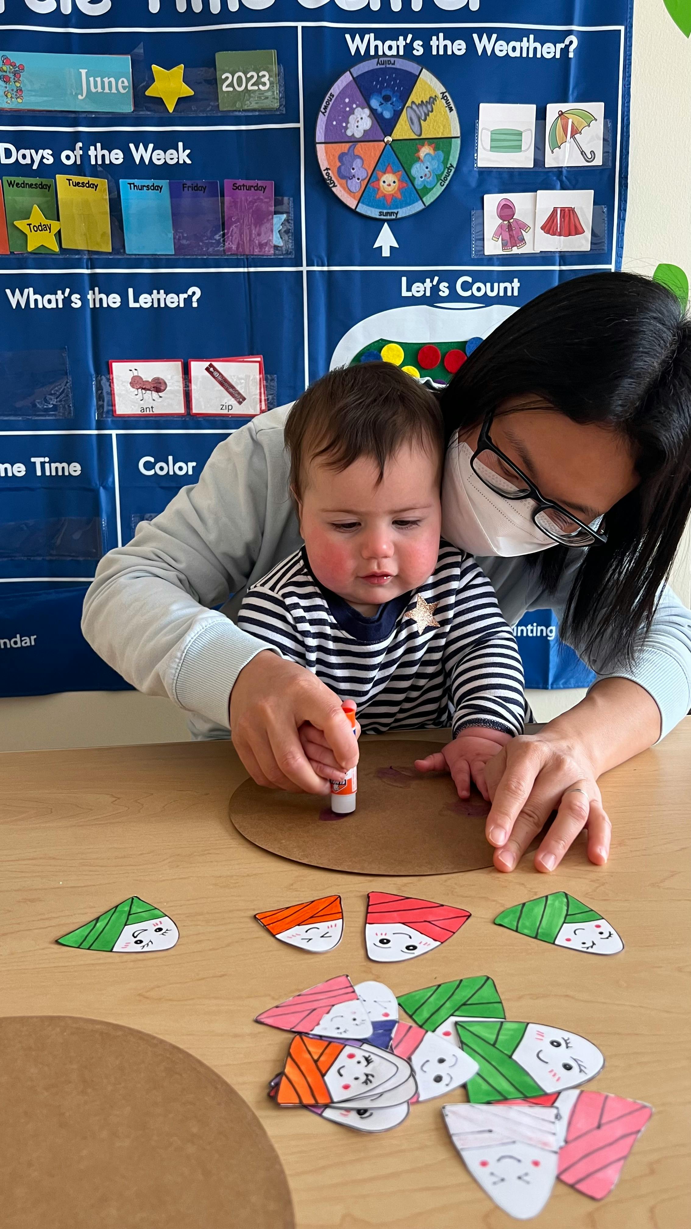 Person helping a child use a glue stick on a craft project