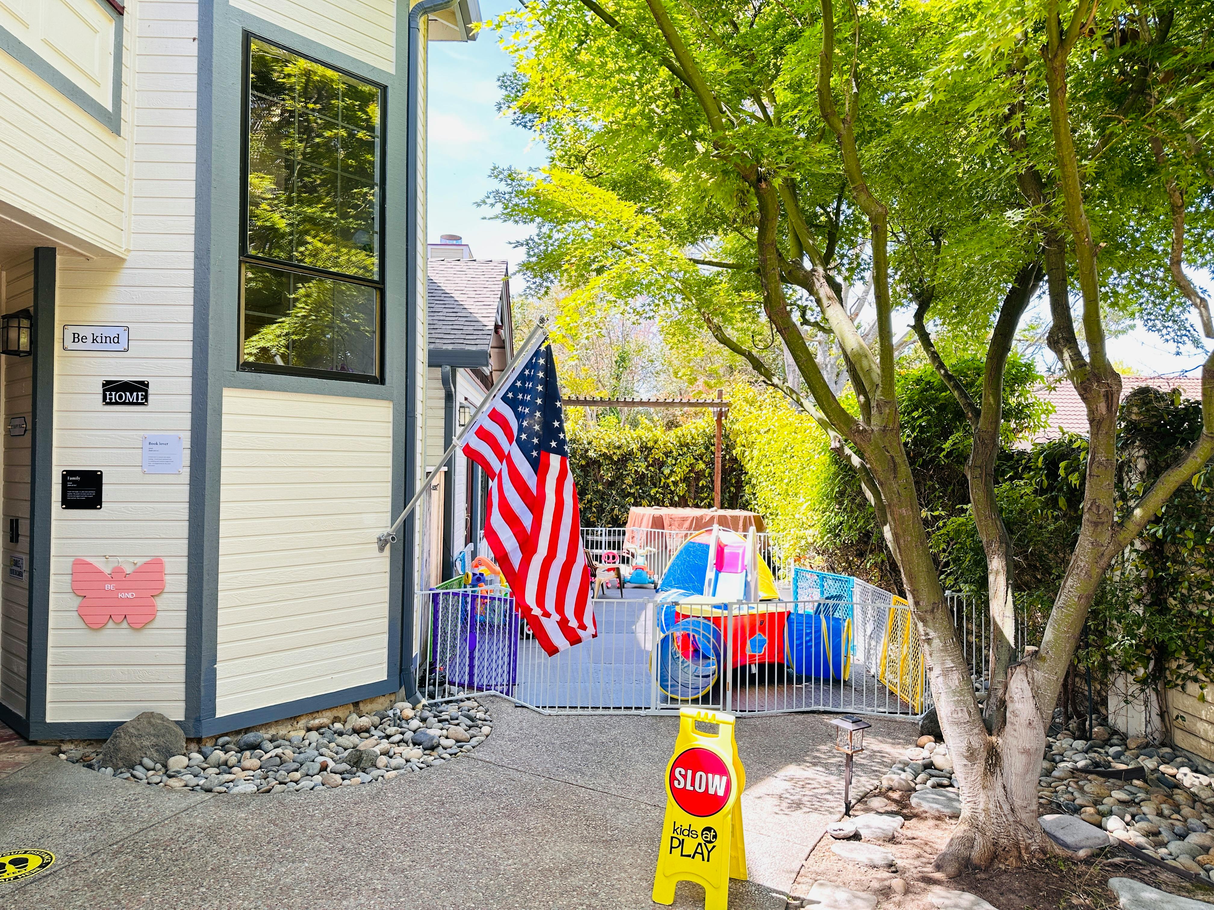 American flag hanging on a building next to a fenced play area