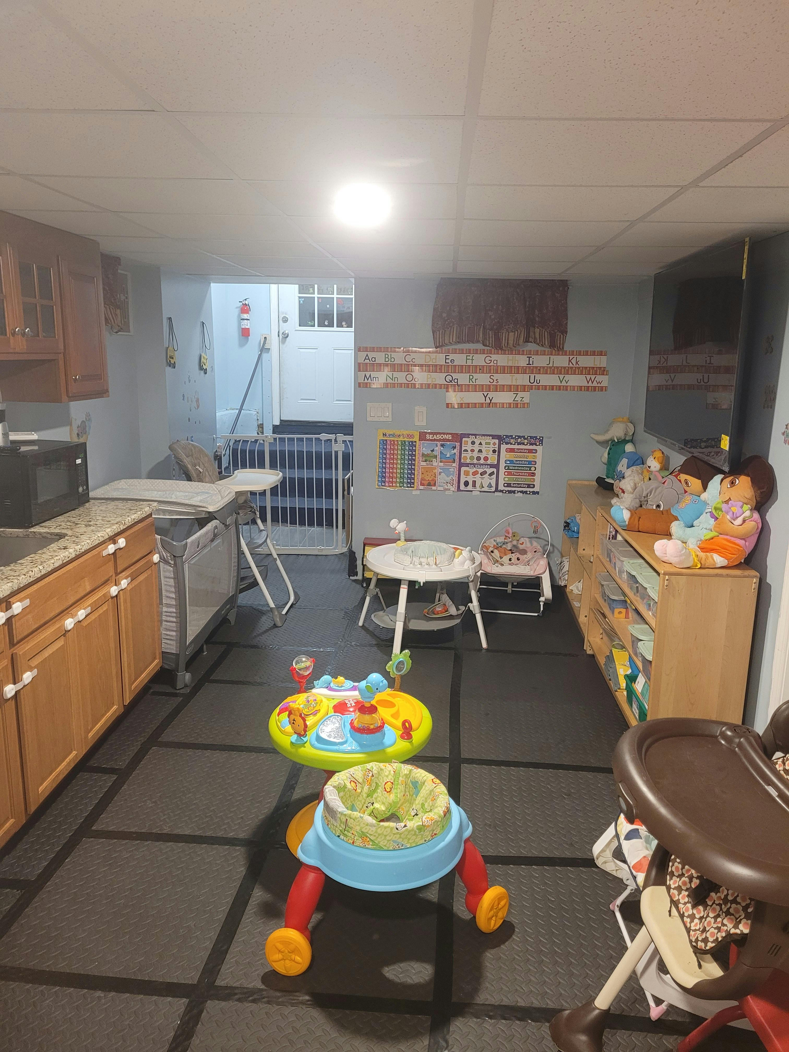 Room with baby items, including a walker, high chair, and changing table