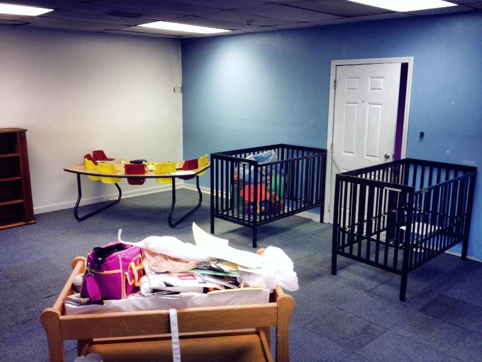 Two cribs and a table with toys in a room