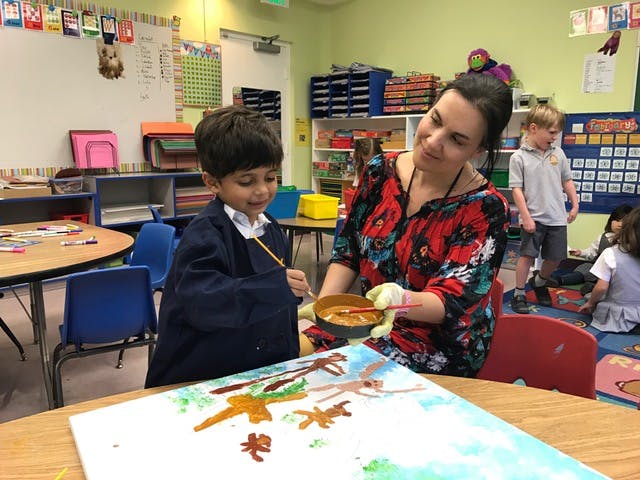 Adult and child painting together in a classroom