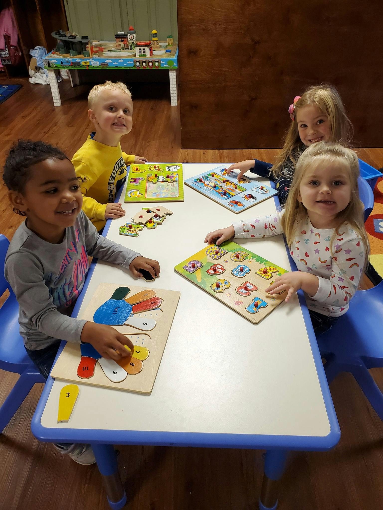 Four children playing with puzzles at a table