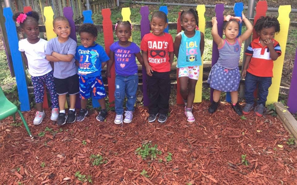Group of children standing in front of a colorful fence