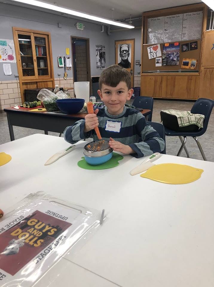 Child mashing food in a bowl at a table