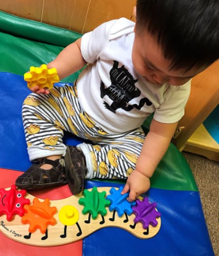 Child playing with a colorful gear toy