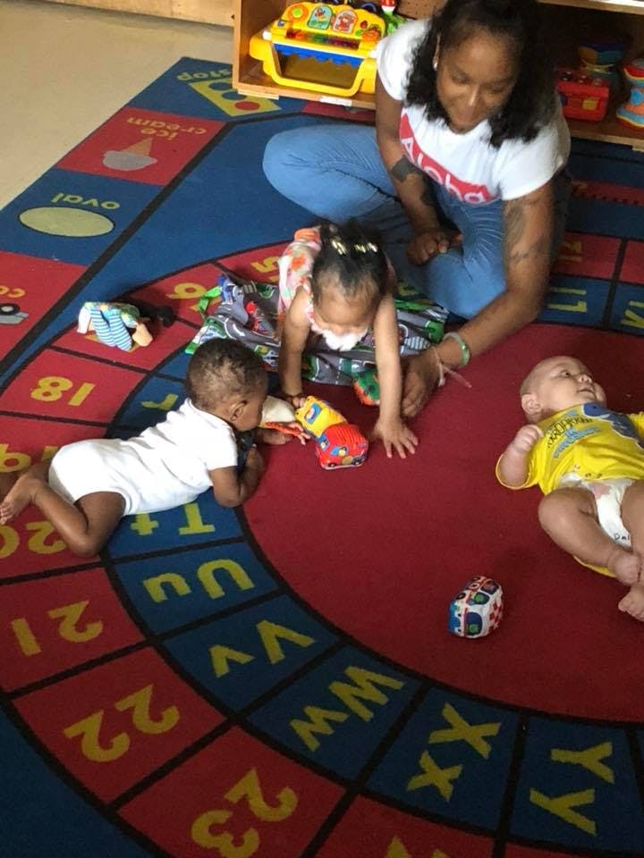 Adult and three children playing on a colorful rug
