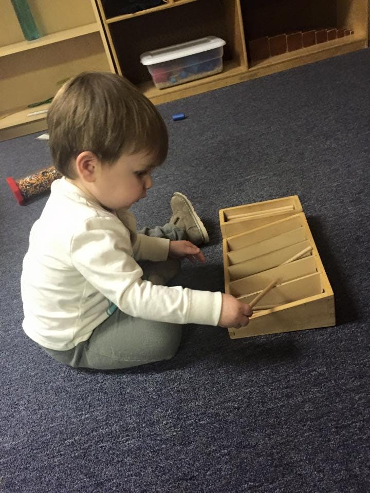 Child playing with a wooden musical instrument on the floor