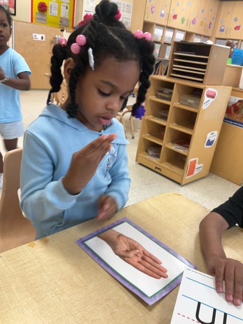 Child looking at a picture of a hand on a table