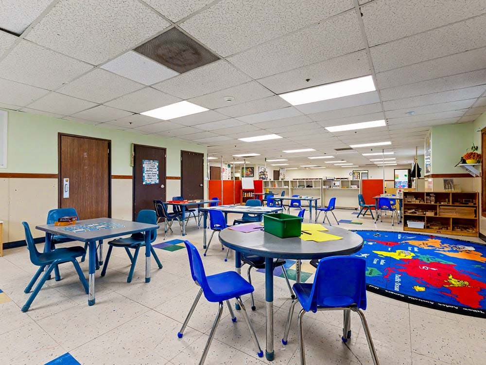 Empty classroom with small tables and blue chairs