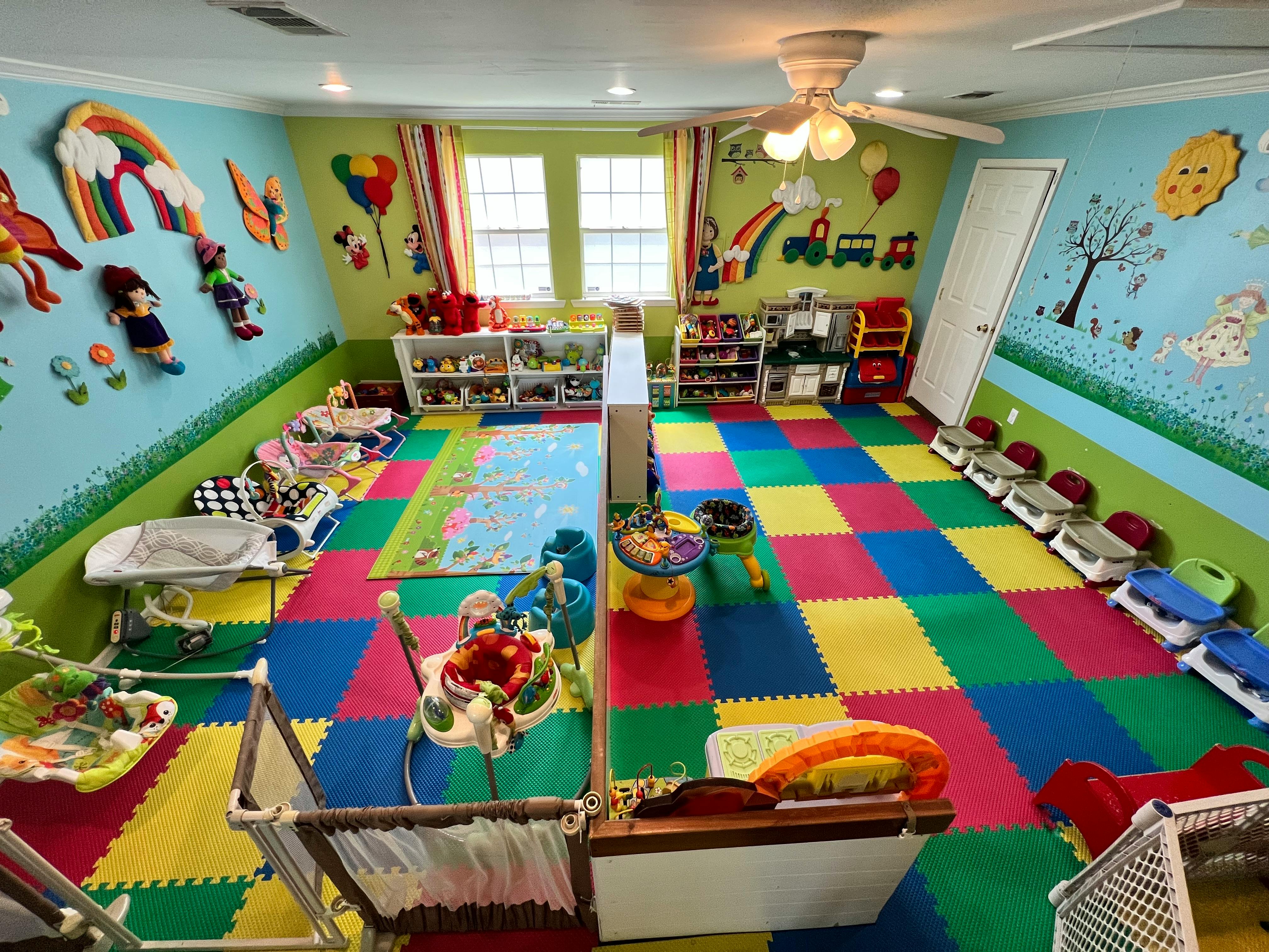 Playroom with colorful floor mats, cribs, and toys