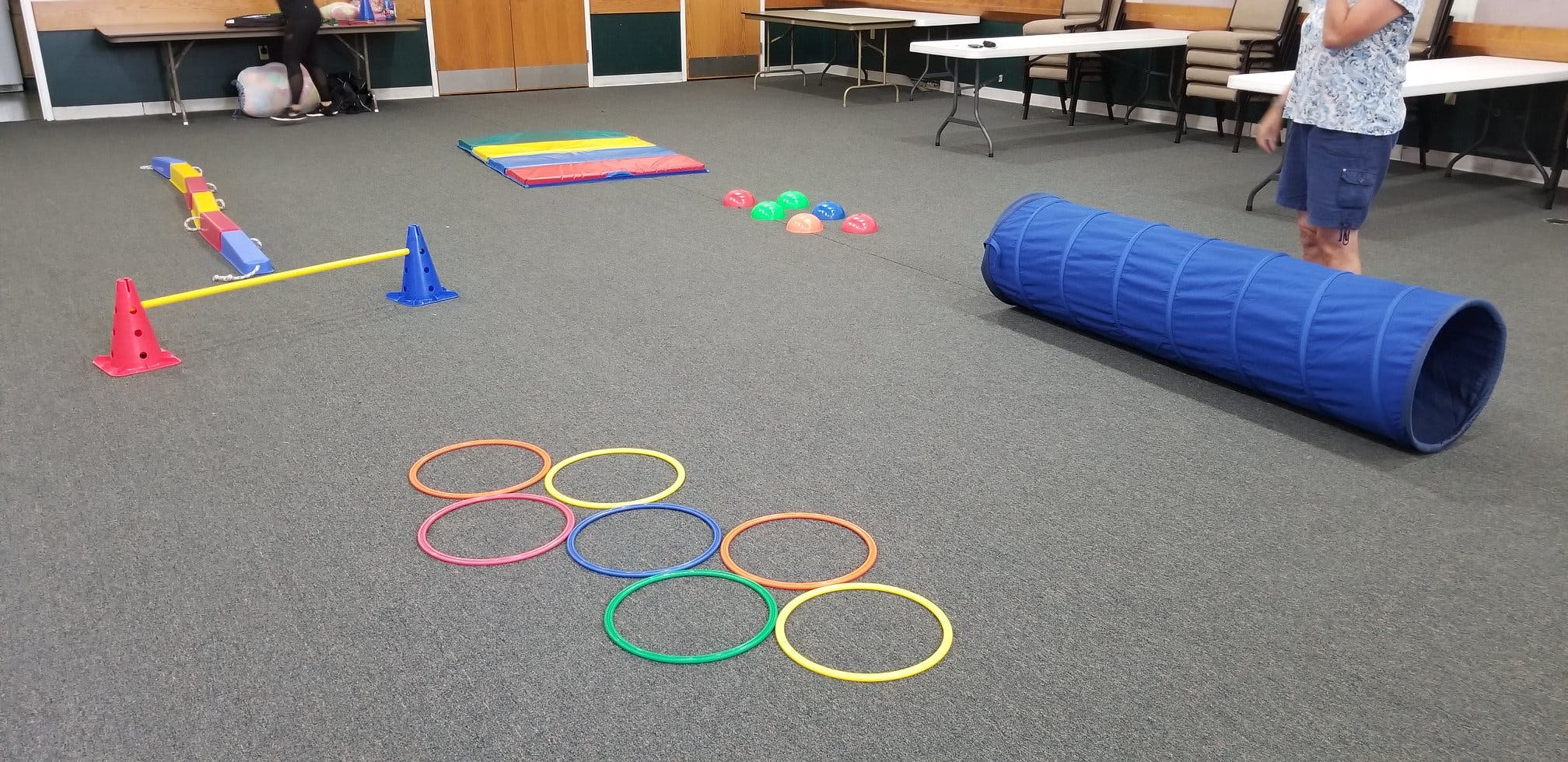 Indoor obstacle course with cones, hoops, tunnel, and balance beam