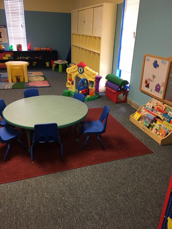 Classroom with small table and chairs, toys, and book display