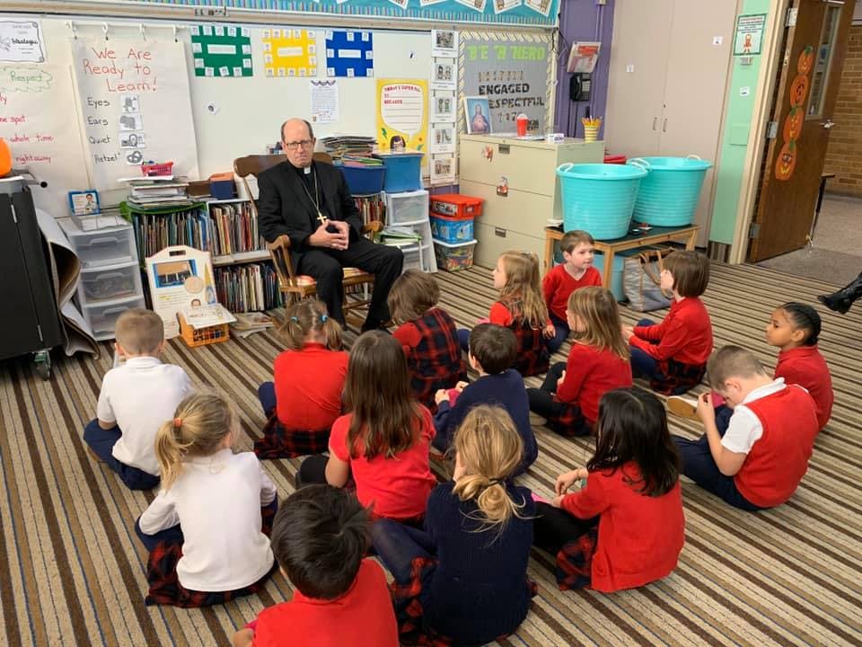 Adult speaking to children sitting on the floor in a classroom
