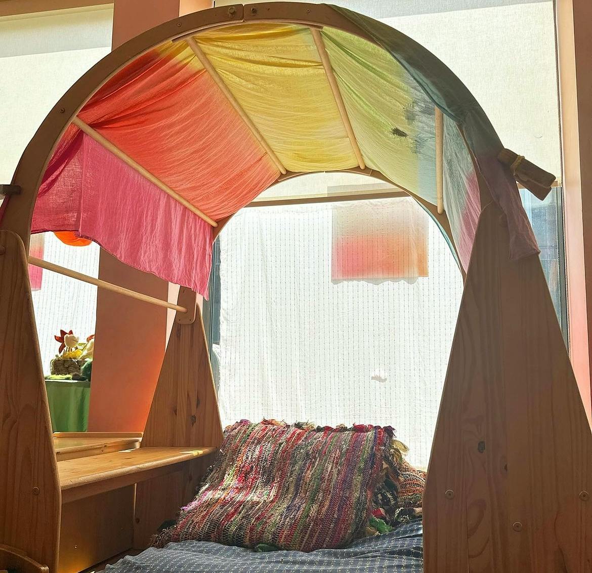 Wooden arch with colorful fabric canopy over a bed