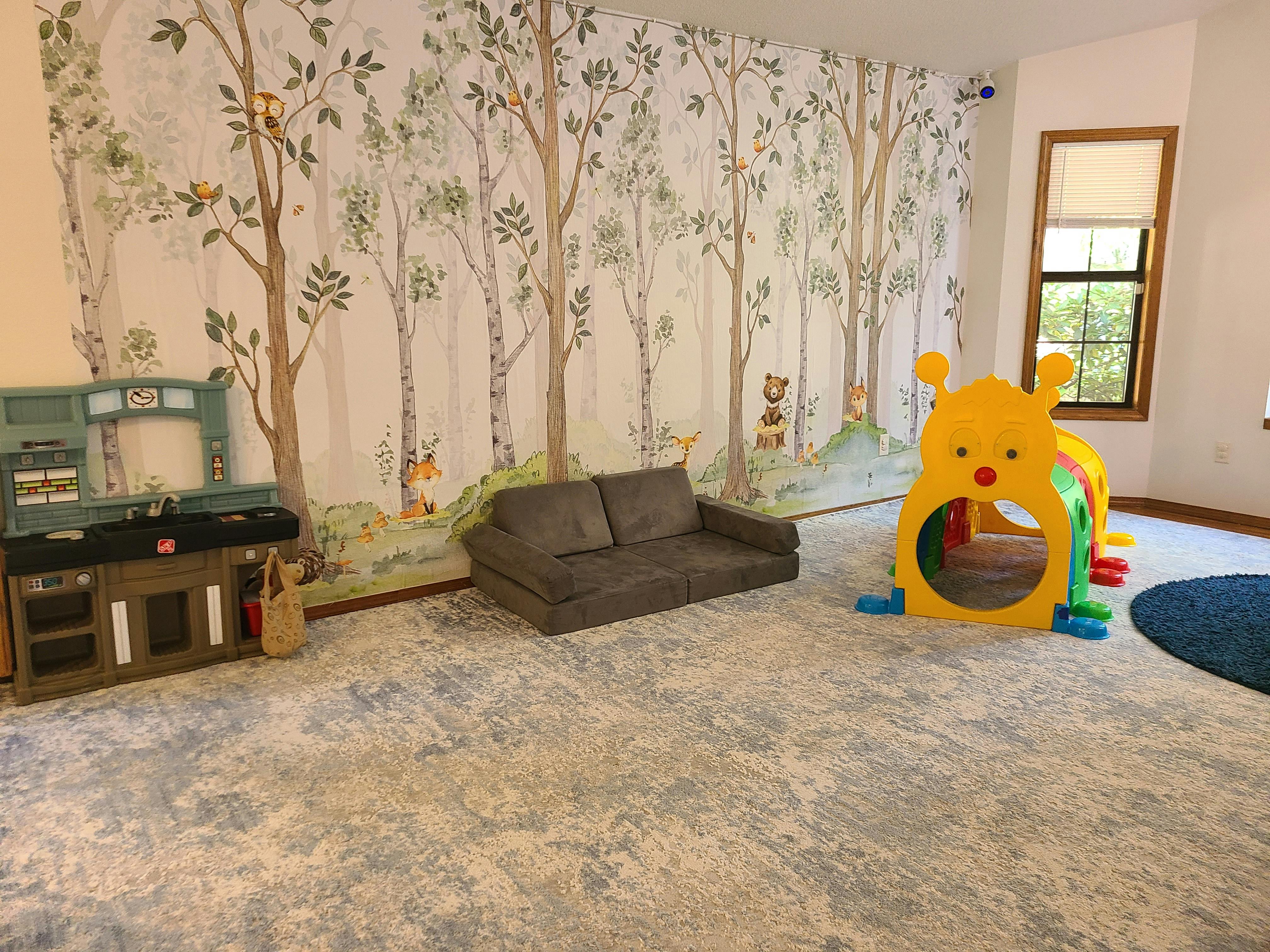 Playroom with a sofa, play kitchen, and yellow caterpillar tunnel
