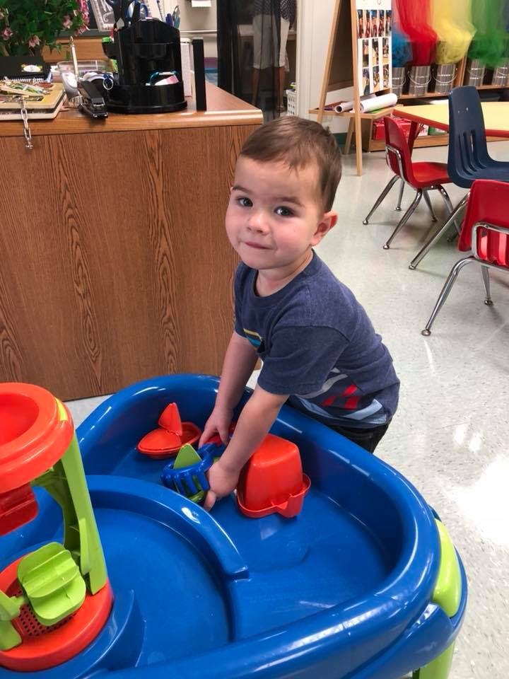 Child playing with toys in a blue water table