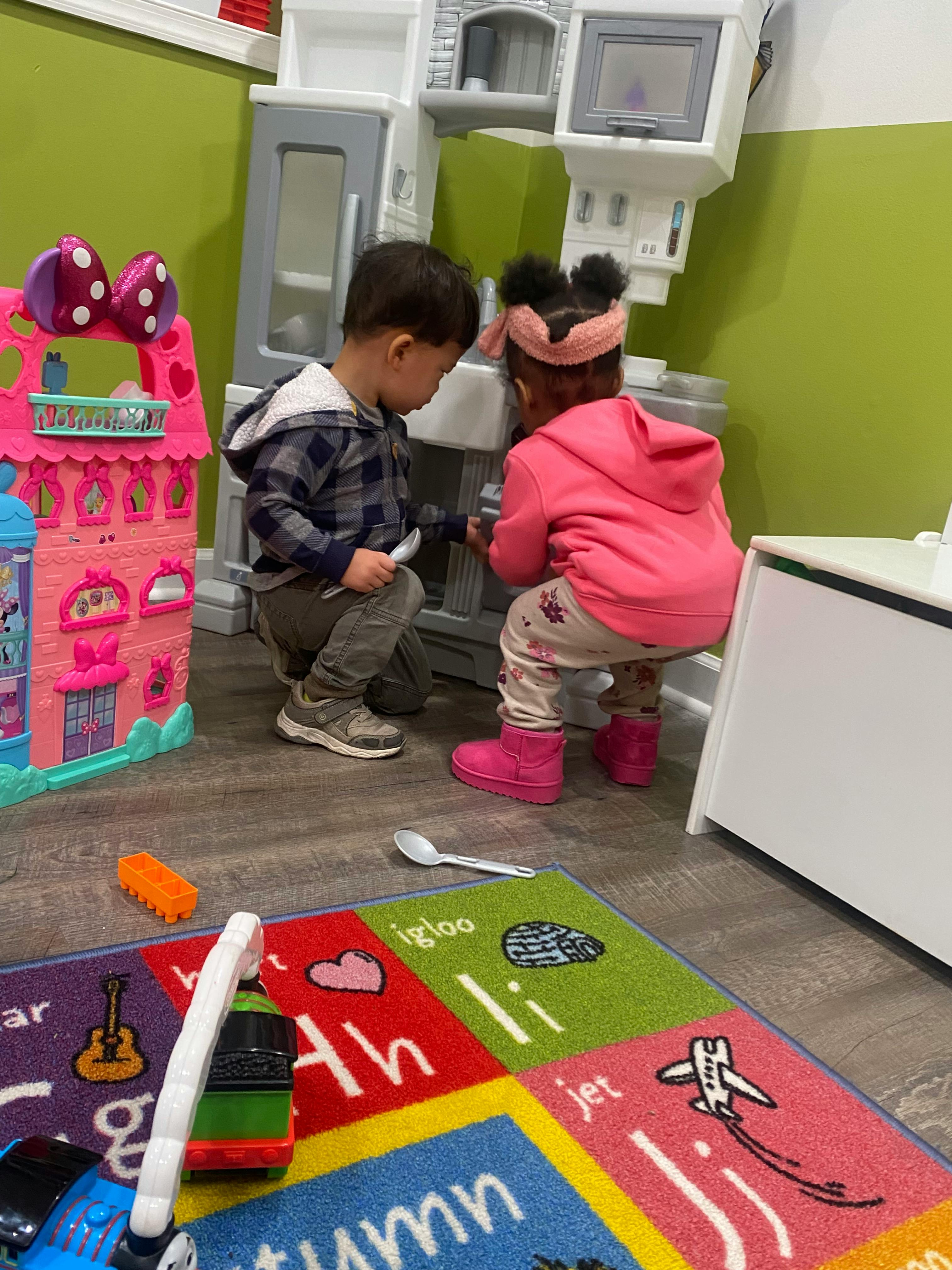 Two children playing with a toy kitchen set