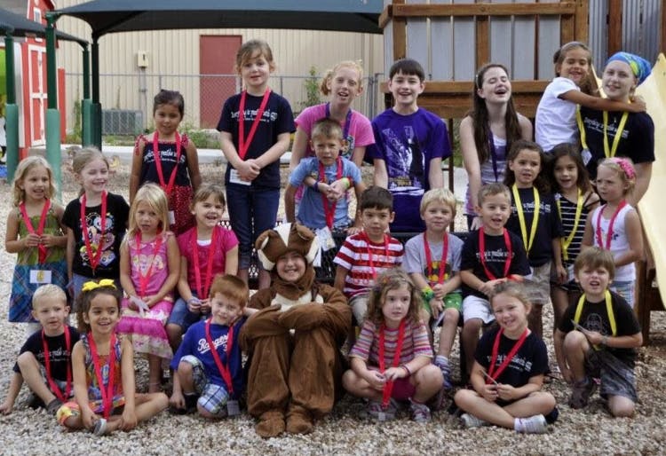 Group of children and teens posing outdoors, some wearing medals