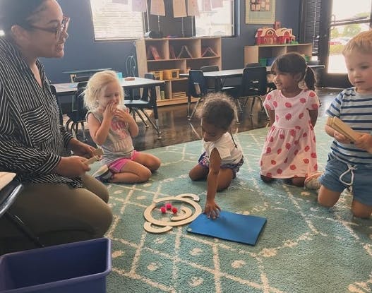 Adult and children sitting on a rug in a classroom