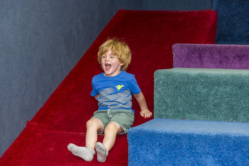 Child sliding down a red ramp