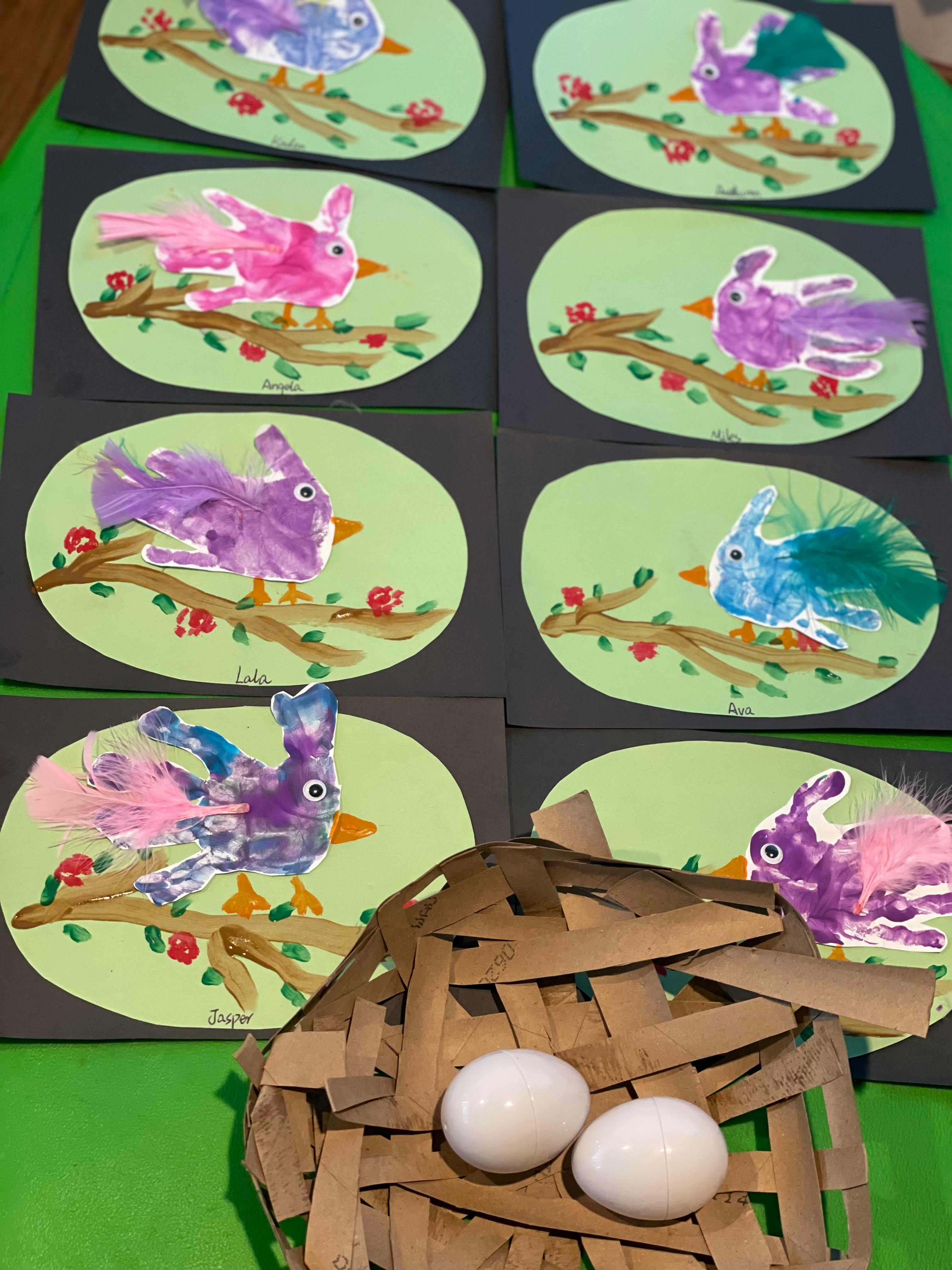 Children's artwork of colorful birds on branches and a craft nest with two eggs