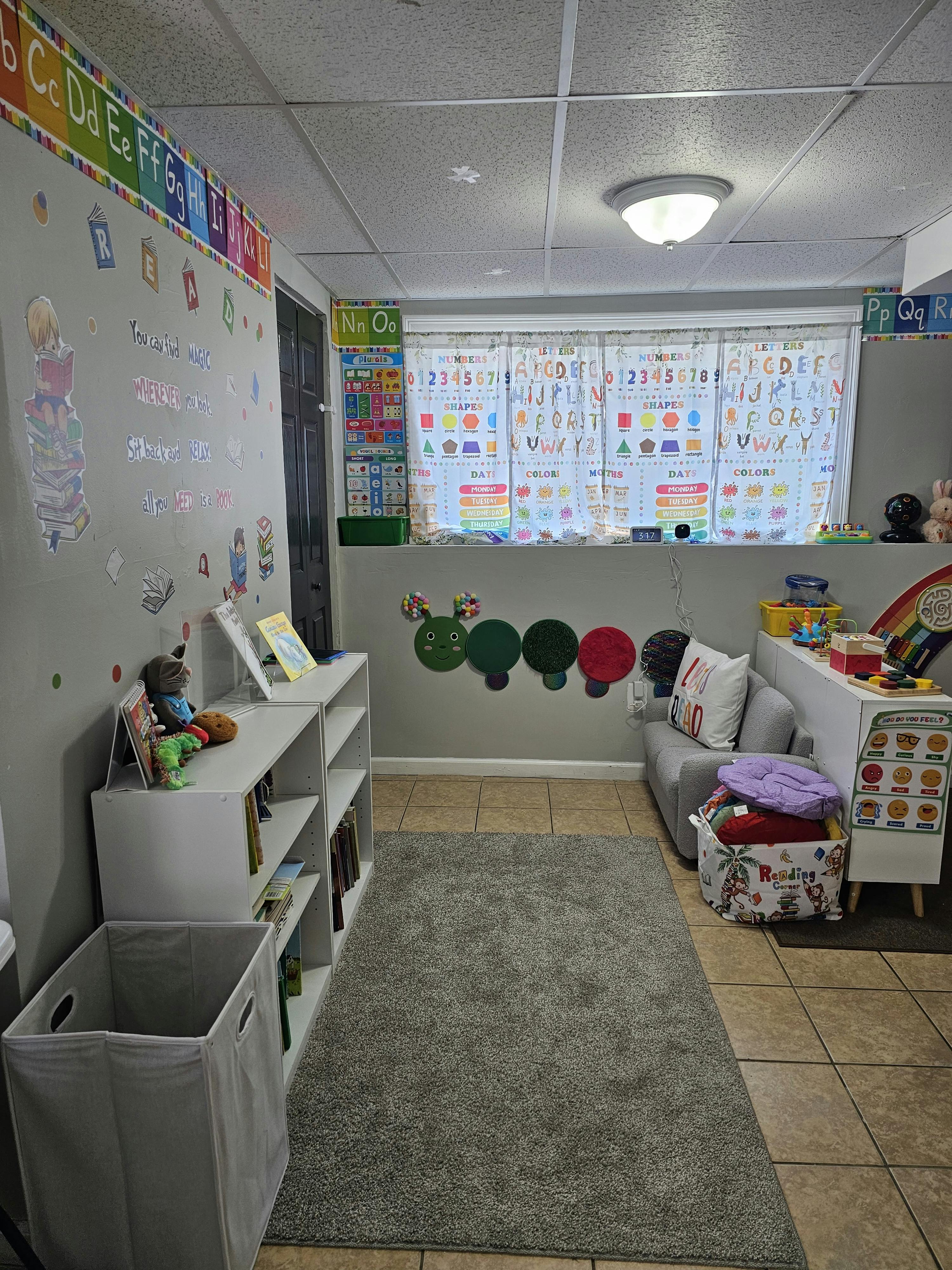 Classroom with educational posters, alphabet, numbers, shapes, colors, and a reading corner