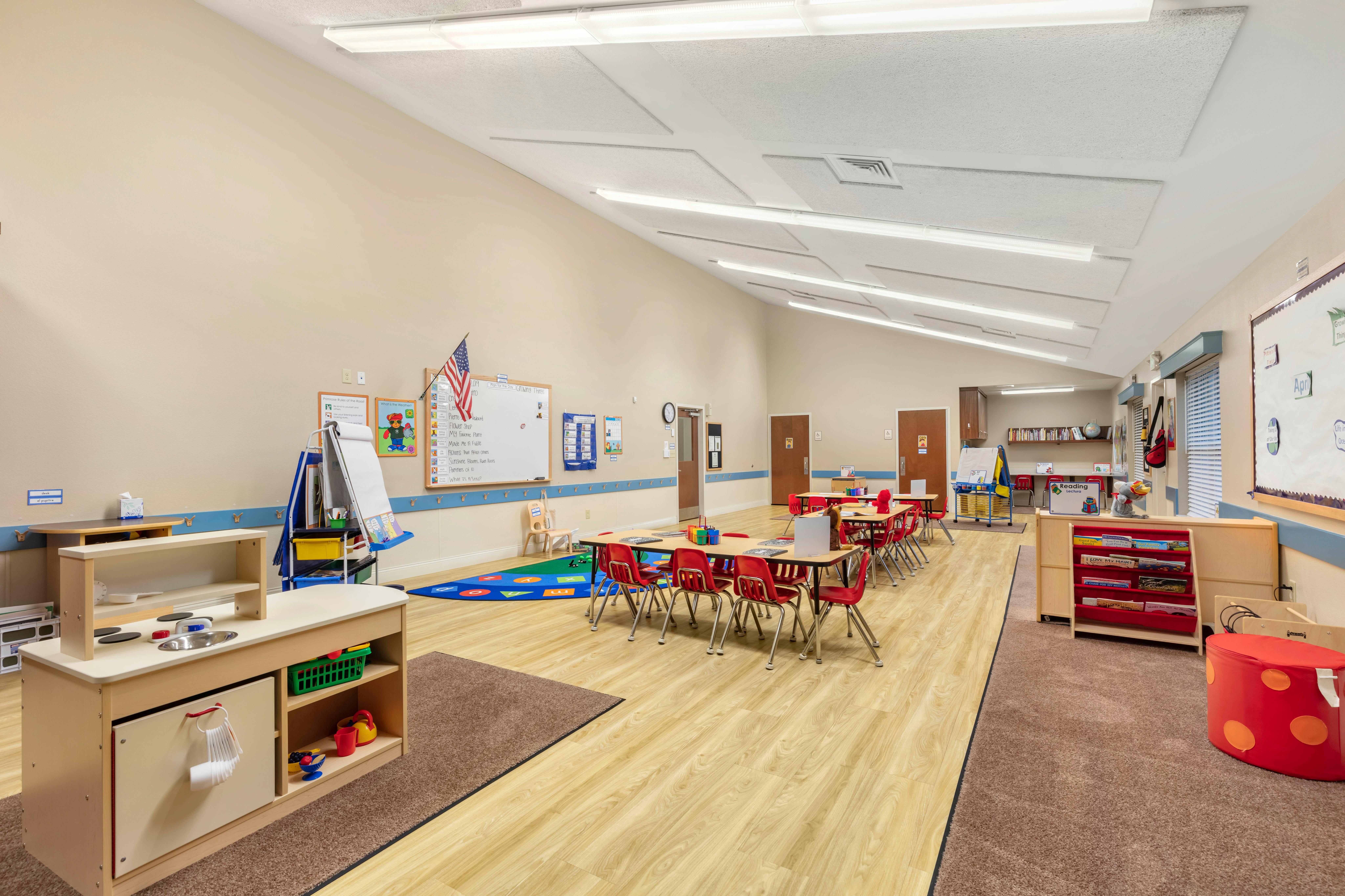 Classroom with small tables and chairs, a play kitchen, and whiteboards