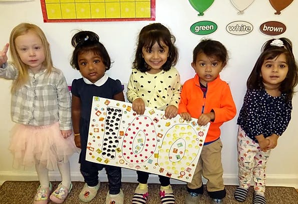 Five children holding a large sign with the number 100 on it