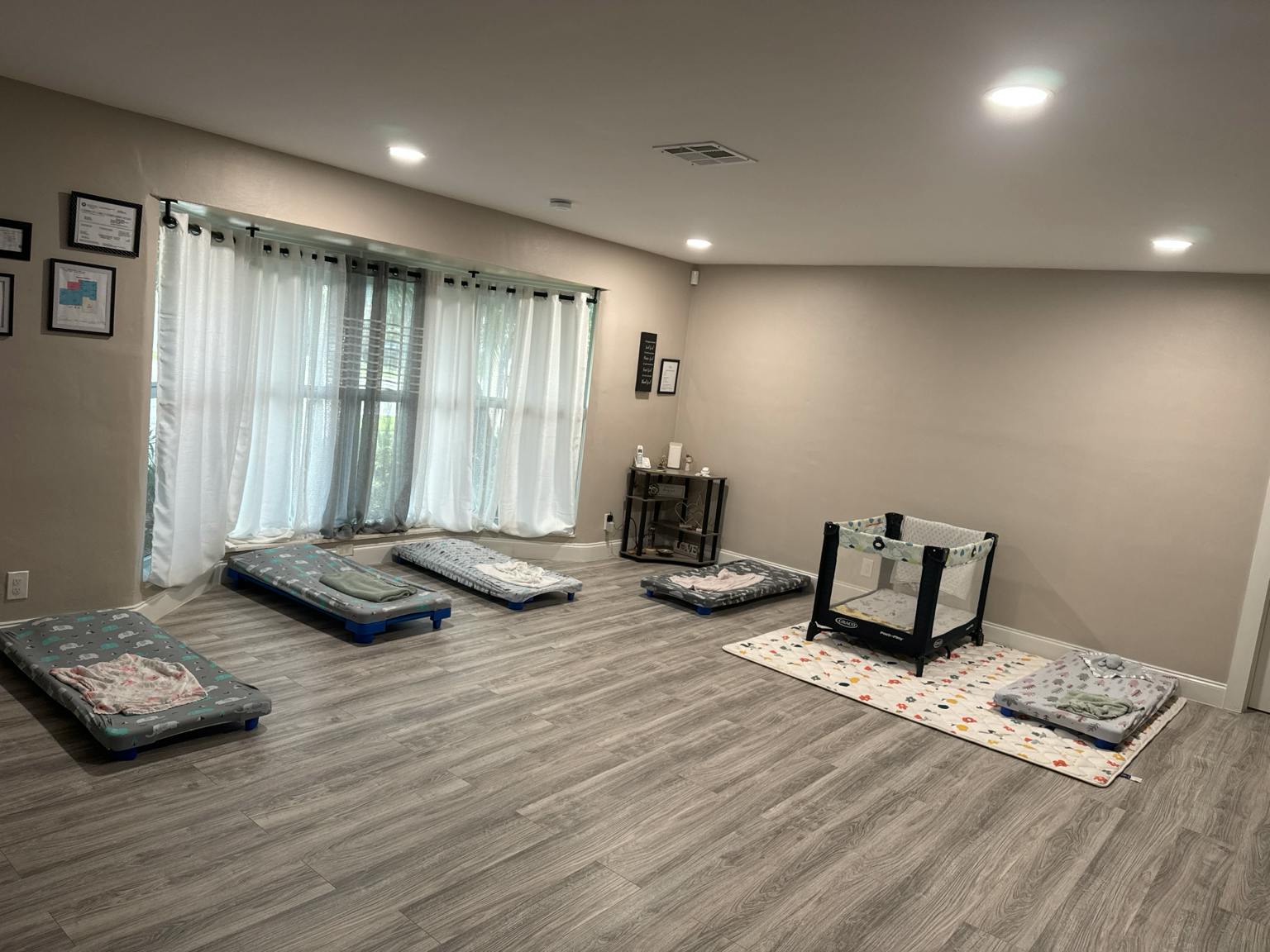 Several small cots and a playpen arranged on a room floor