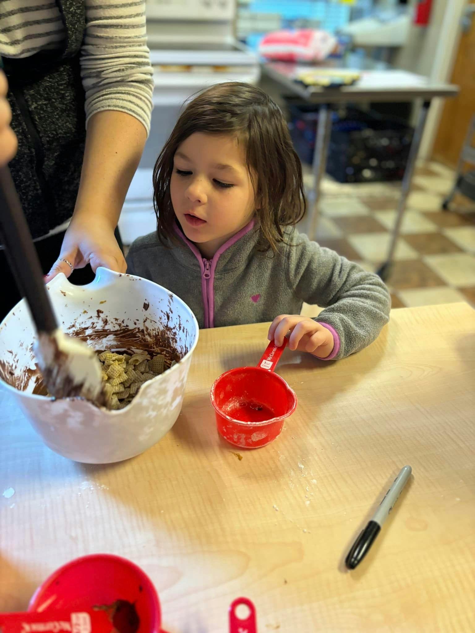 Person and child mixing ingredients in a bowl