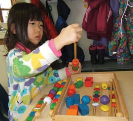 Child playing with colorful wooden blocks and beads