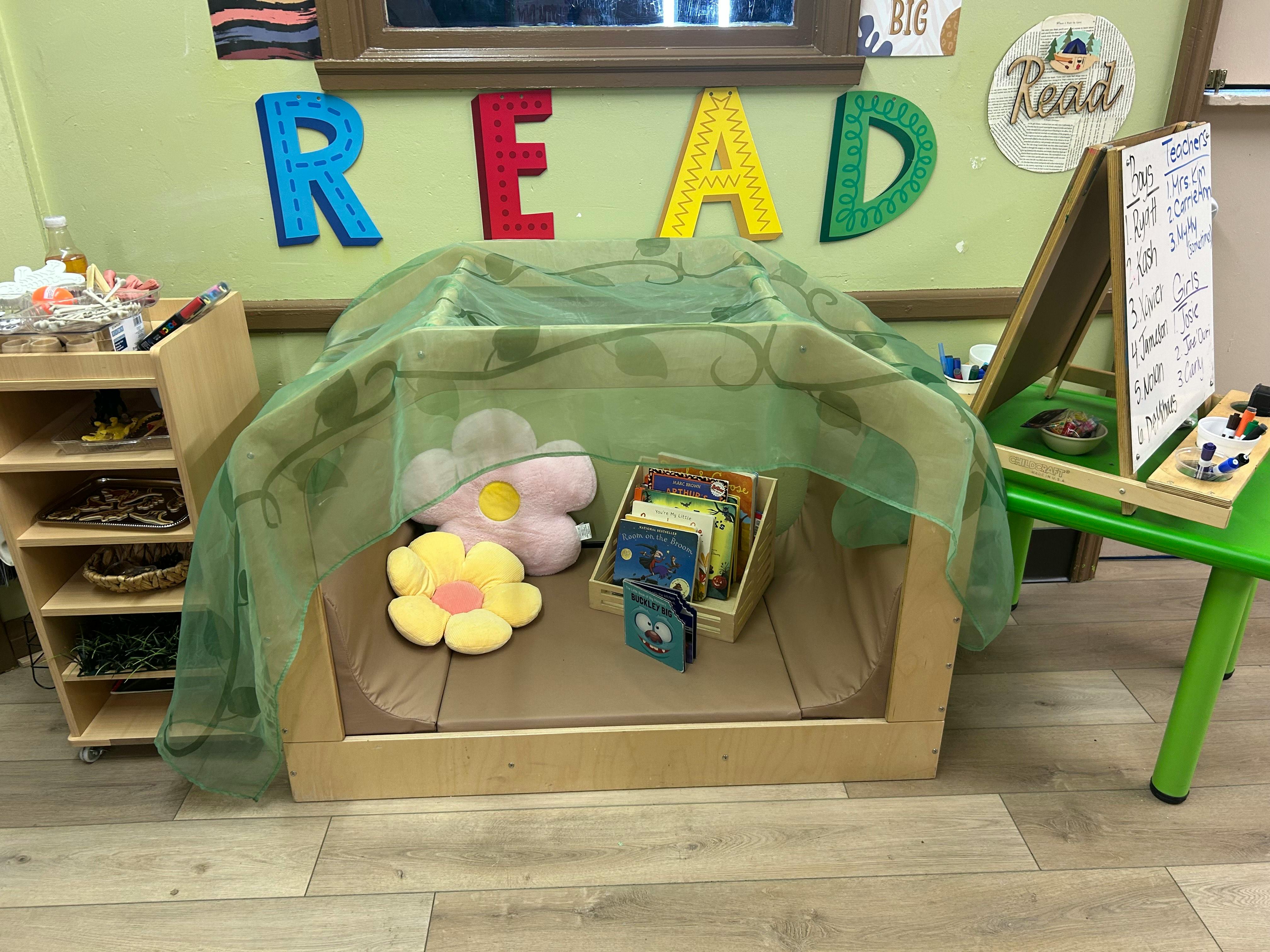 Reading nook with pillows and books under a sheer green canopy