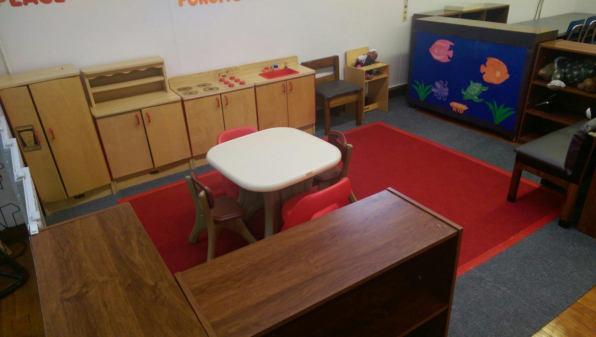 Classroom with small table and chairs, wooden cabinets, and a blue display